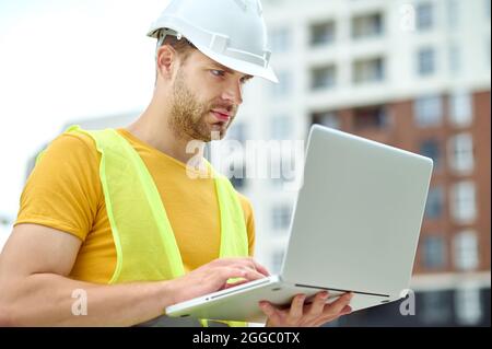Concentrated male engineer working on his computer outdoors Stock Photo