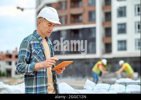 Handsome concentrated engineer reading an email on his gadget Stock Photo