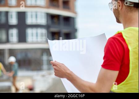 Experienced male engineer in a hardhat studying a building plan Stock Photo