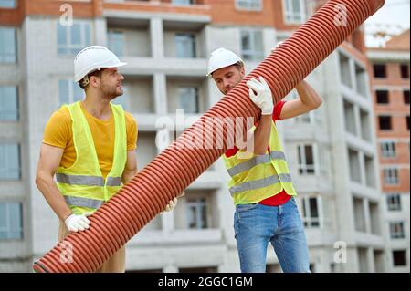 Men in hardhats and cotton gloves installing the sewer line Stock Photo