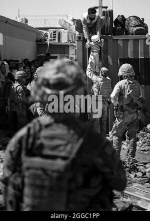 An Afghan man hands his child to a British Paratrooper assigned to 2nd Battalion, Parachute Regiment while a member of 1st Brigade Combat Team, 82nd Airborne Division conducts security at Hamid Karzai International Airport in Kabul, Afghanistan, August 26, 2021. The 82nd Abn. Div. continues to help facilitate the safe evacuation of U.S. citizens, Special Immigrant Visa applicants, and other at-risk Afghans out of Afghanistan as quickly and safely as possible. (U.S. Army courtesy photo) Stock Photo