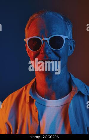 Front view graphic colored portrait of senior man wearing sunglasses in red and blue, copy space Stock Photo