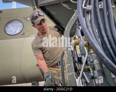A Paratrooper assigned to the 82nd Combat Aviation Brigade, 82nd Airborne Division prepares a  CH-47 Chinook to load onto a U.S. Air Force C-17 Globemaster III at Hamid Karzai International Airport in Kabul, Afghanistan, August 28. The Chinook. is one of the pieces of equipment returning to the U.S. as the military mission in Afghanistan comes to an end. Stock Photo