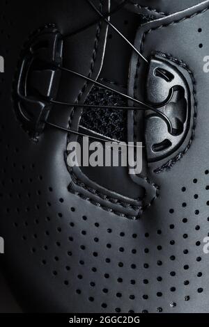 Sports shoes made of black perforated leather in a dark key. Close-up Stock Photo