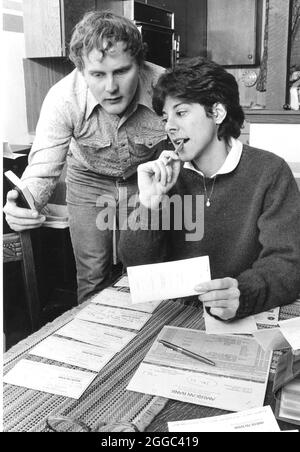 ©1986 Anglo couple in '30s doing budgets and balancing checking account at home.  Bob and Janis Daemmrich Stock Photo