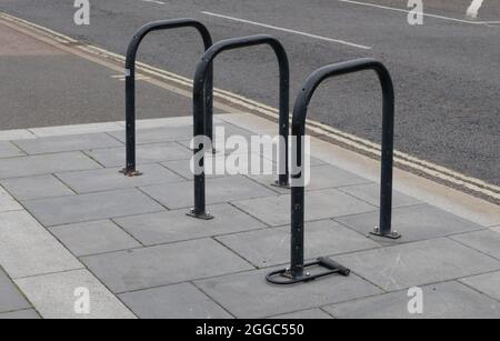 Black cycle rack or stand on pavement beside road with double yellow line Stock Photo