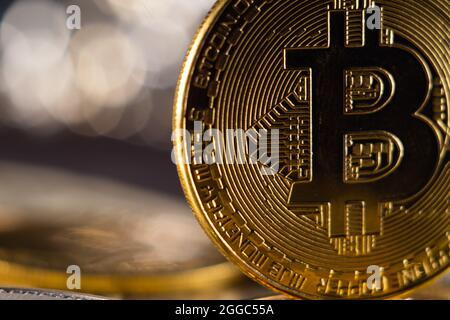Selective focus shot of golden bitcoin standing on pile of coins Stock Photo