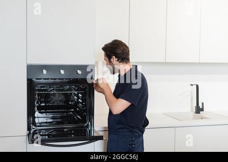 workman repairing electric built-in oven in modern kitchen Stock Photo