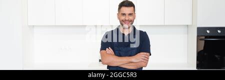 happy workman standing in kitchen with crossed arms, banner Stock Photo