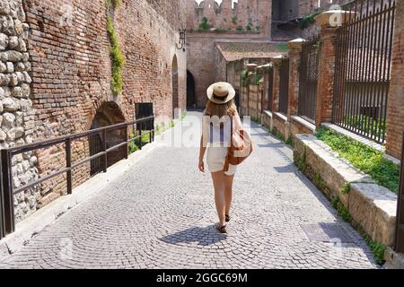 Beautiful tourist woman walking in the medieval city of Verona on Castelvecchio bridge, Italy Stock Photo