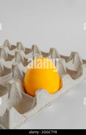 One yellow egg in a cardboard box. Feast of Bright Easter. Stock Photo