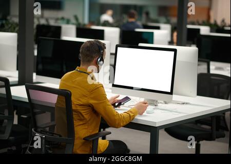 Manager in headphones works on computer, IT office Stock Photo