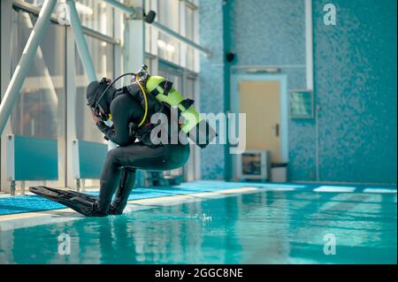 Male diver in scuba gear jumps into the pool Stock Photo