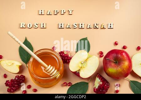 Happy Rosh Hashanah. Traditional Jewish holiday New Year. Apples, pomegranates and honey on a yellow background. Inscription of wooden letters. Stock Photo