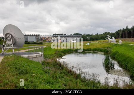 Transinne, Wallonia, Belgium - August 10, 2021: Looking at Euro Space Center from back of green domain with antenna and planet statues under rainy clo Stock Photo