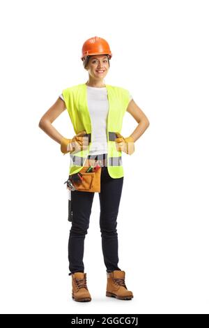 Full length portrait of a young female construction worker wearing a hardhat and a tool belt isolated on white background Stock Photo