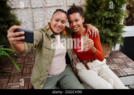 Two young women taking selfie photo via smartphone during outdoor party at rooftop Stock Photo