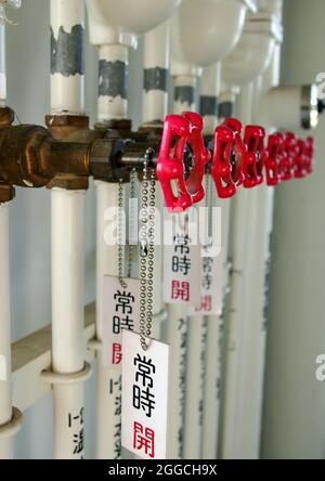 Red water fauceta and white pipes, in shallow focus Stock Photo