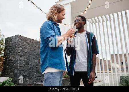 Waist up portrait of two young men chatting during outdoor party at rooftop, copy space Stock Photo