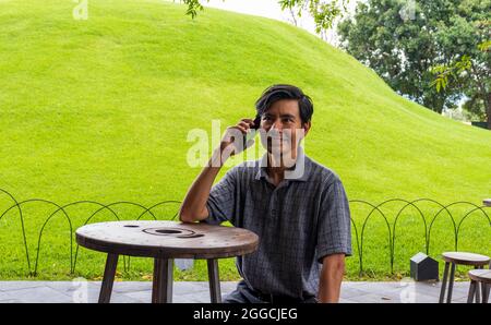 Hispanic man using cellphone in the park Stock Photo