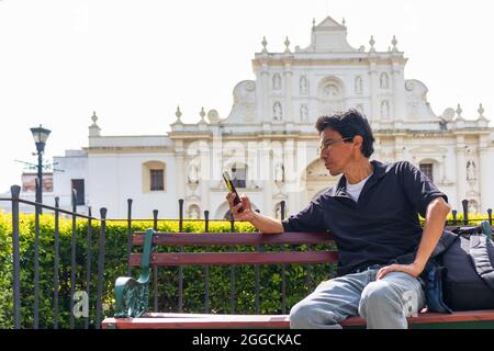 man using his cellphone in front of the main cathedral of antigua guatemala Stock Photo