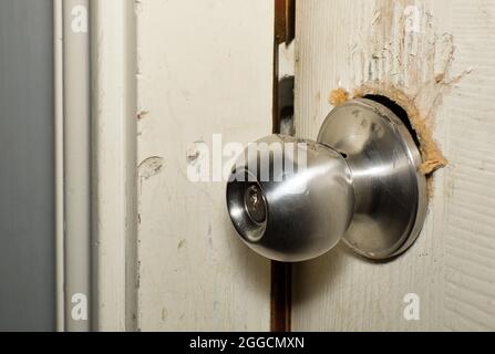 Broken modern doorknob closeup with signs of forced entry, criminal activity and door slightly open. Stock Photo