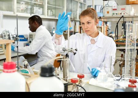 Young female lab technicians working with reagents and test tubes Stock Photo