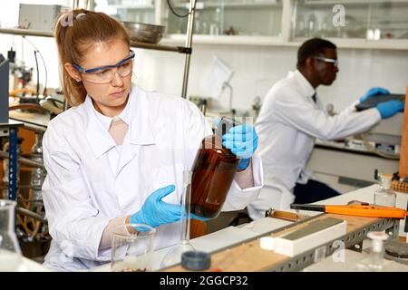 Serious woman lab scientist in glasses working with reagents and test tubes Stock Photo