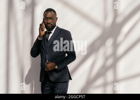 Young businessman with tense facial expression talking on mobile phone in front of camera Stock Photo