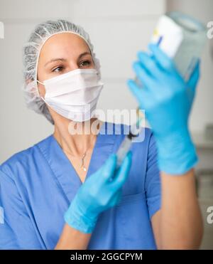 Nurse fills syringe with injection solution Stock Photo