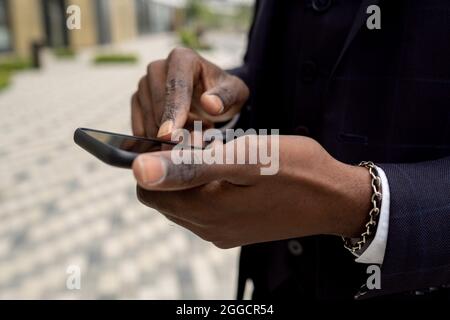 Hands of African businessman pointing at smartphone screen in front of camera Stock Photo