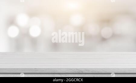 White wood table top over blur bokeh light background. White  wooden counter, desk, shelf for product display, mockup, template. Stock Photo