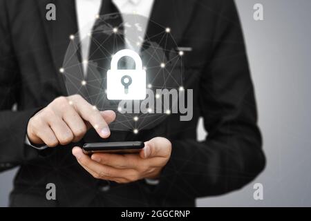 Businessman holding mobile phone with shield lock. Cyber security data protection and information technology network concept. Stock Photo