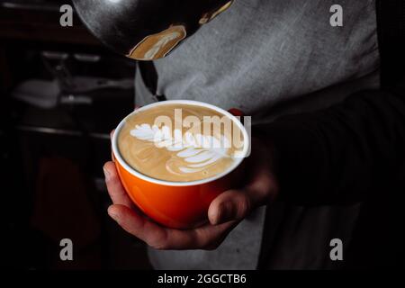 Latte coffee, barista pouring milk in to coffee, making coffee with latte art Stock Photo
