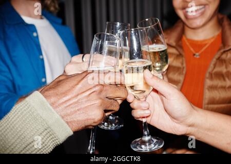 Close up of young people clinking champagne glasses at party, shot with flash, copy space Stock Photo