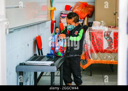 Mexico, Mexico. 29th Aug, 2021. A kid wearing a face mask as a preventive measure against the spread of coronavirus holds his backpack in his classroom. Schools in Mexico return to face-to-face classes of the basic level for the 2021-2022 school year. The Secretary of Public Education confirmed that the return to the classroom is not mandatory for parents. (Photo by Guillermo Diaz/SOPA Images/Sipa USA) Credit: Sipa USA/Alamy Live News Stock Photo