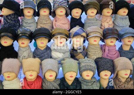 Winter and autumnal warm hats on mannequins in a shop window Stock Photo