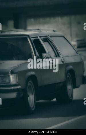 Classic station wagon at speed on road, monochrome conversion. Stock Photo