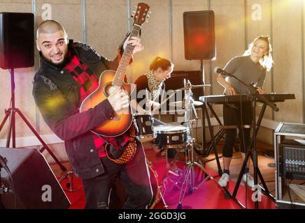 Bearded guy soloist playing guitar in studio Stock Photo