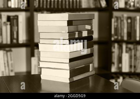 A stack of different books in a large library selected by the reader lies on table. black - white photo. Stock Photo