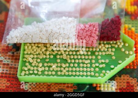 Multicolored diamond strases in container for handmade process of creation of diamond painting 3d from rhinestones Stock Photo