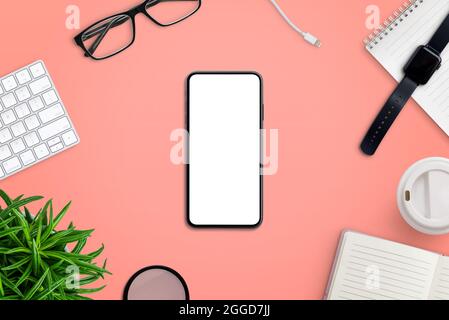 Modern smart phone on work desk surrounded by office supplies. Creative flat lay composition on red surface Stock Photo