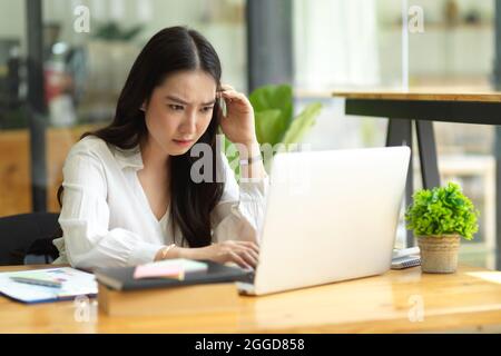 Pensive serious businesswoman, solving problem, reading email on laptop computer, thoughtful, stressed business worker Stock Photo