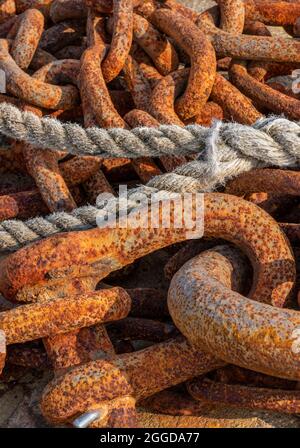 rusty old chain with rope, corroded old shackle, discarded shackle and chain going rust, close-up of chain and rope, links, maritime, nautical, rusty. Stock Photo