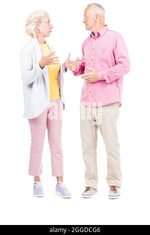 Vertical full length shot of senior man and woman standing to each other talking about something, white background Stock Photo