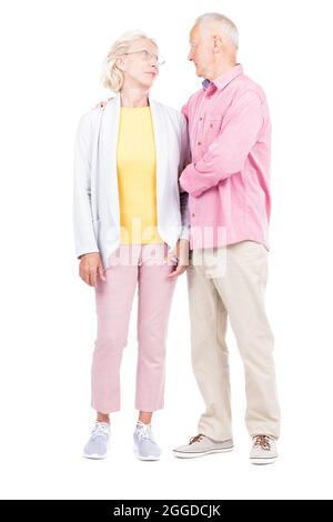 Vertical full length shot of of senior married man and woman standing together looking at each other Stock Photo