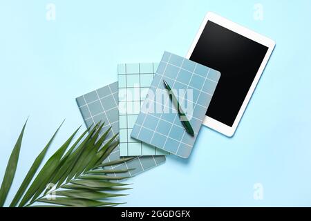 Composition with notebooks, pen, tablet computer and palm leaf on color background Stock Photo