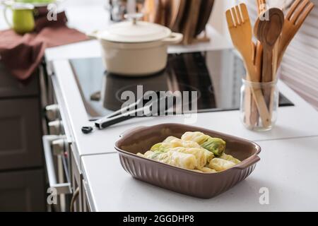 Baking dish with raw stuffed cabbage rolls on table in kitchen Stock Photo
