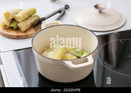 Cooking pot with raw stuffed cabbage rolls on electric stove at kitchen Stock Photo