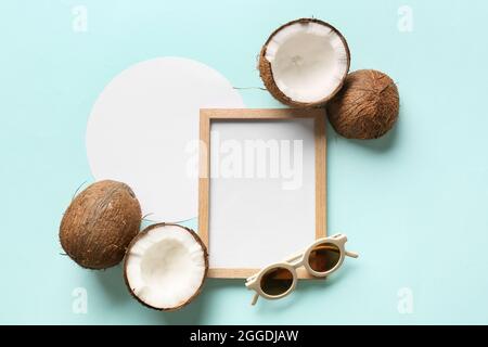 Composition with empty picture frame, blank card, coconuts and sunglasses on color background Stock Photo